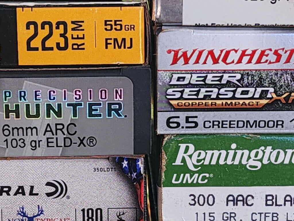 pile of .223 Remington ammo boxes with mixed rifle calibers for comparison