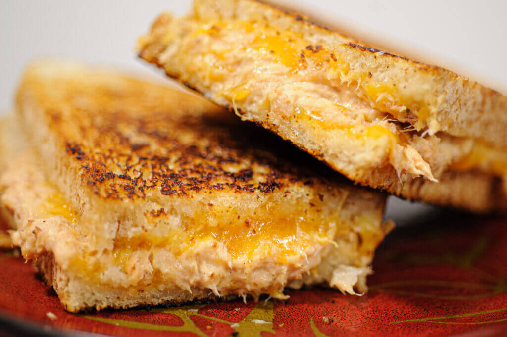 Crispy grilled fish sandwich with smoked trout and cream cheese, sliced and stacked for a juicy melt.