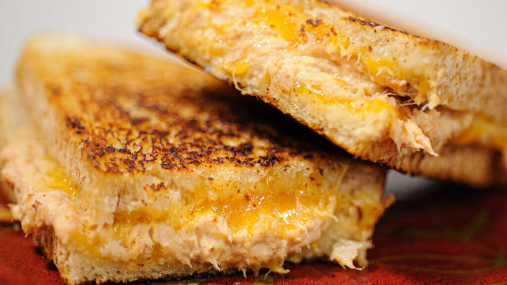 close up of sandwhich cut in half, one half leaning atop the other.