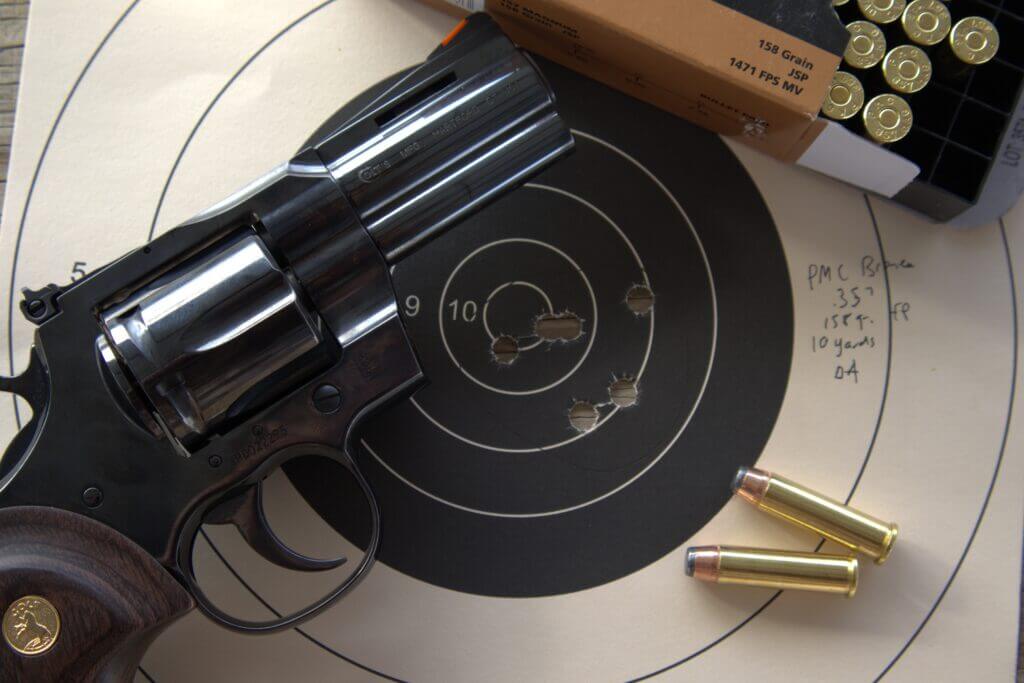 blued Colt Python revolver with paper target and .357 Magnum ammunition after accuracy testing