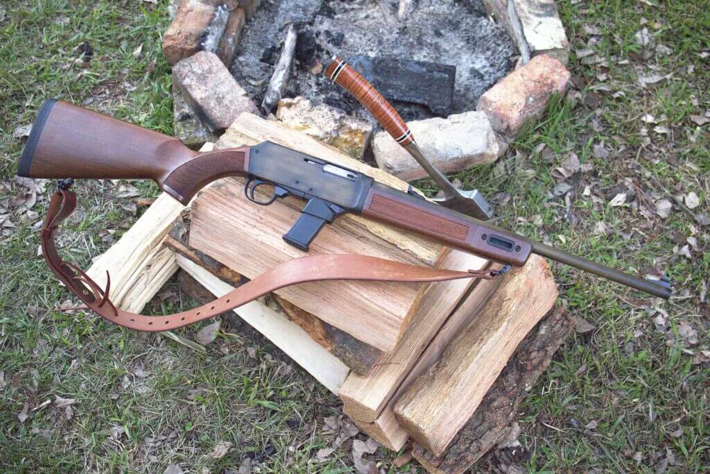 Henry Homesteader M-LOK 9mm carbine resting on firewood with walnut stock and brushed bronze finish