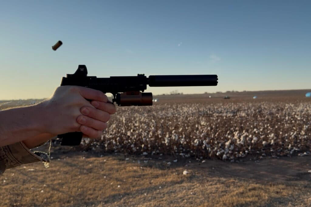 Shooter firing the M&P22X with suppressor attached during range session