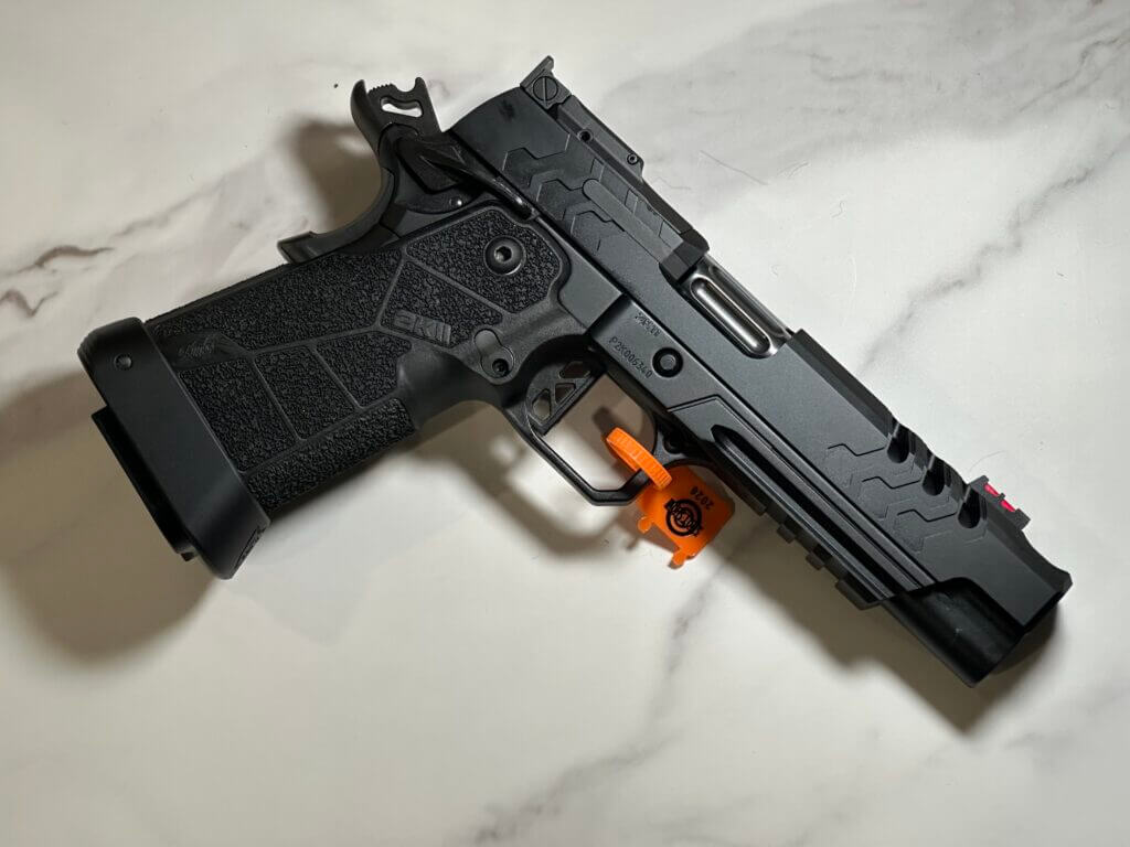 There is a black handgun laying on a white granite countertop. 