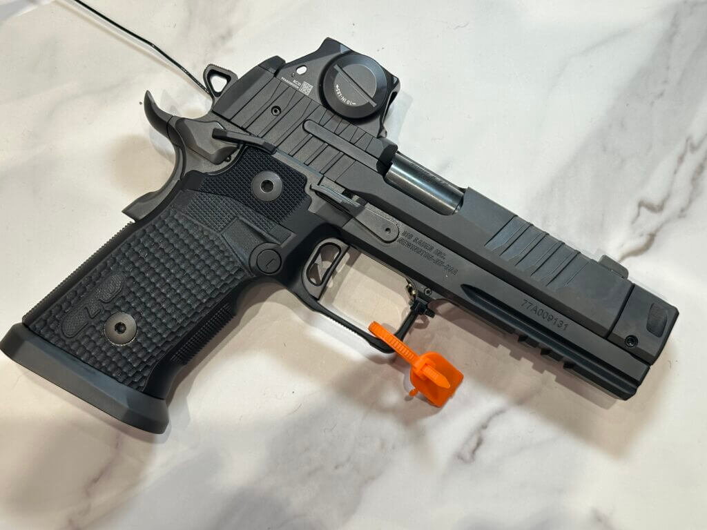 A black handgun rests on a white marble countertop.