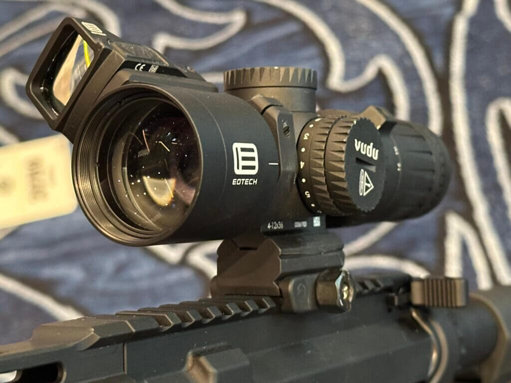Looking at the objective lens of the optic, there is a red dot-sight mounted above the scope at a 45 degree offset.