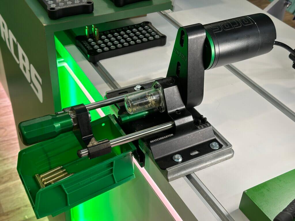 There is a green and black machine that is bolted to a white table.