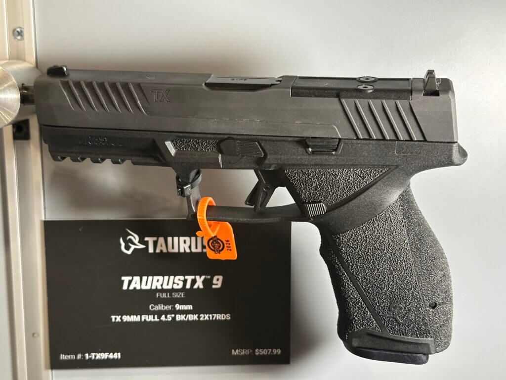 A pistol is pointing from left to right and a placard is shown behind it with details.