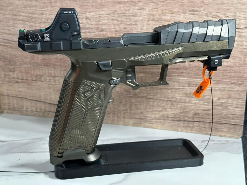 A green and black pistol rests on a display stand.