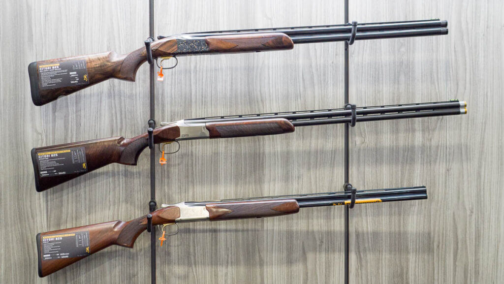 Three shotguns hanging on a wall rack.