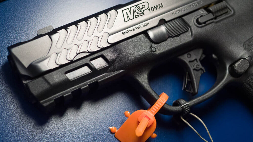 Close up view of the front left side of the gun laying on a blue table with the gun facing left.