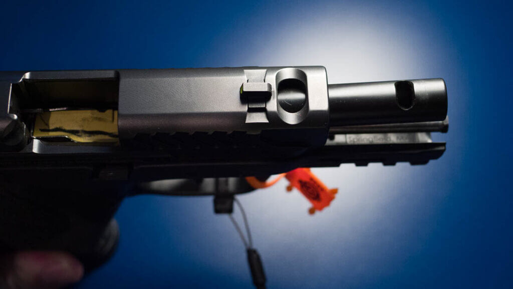 Close up view of the front top side of the gun wioth the slide retracted to show both the ported slide and the ported barrel.