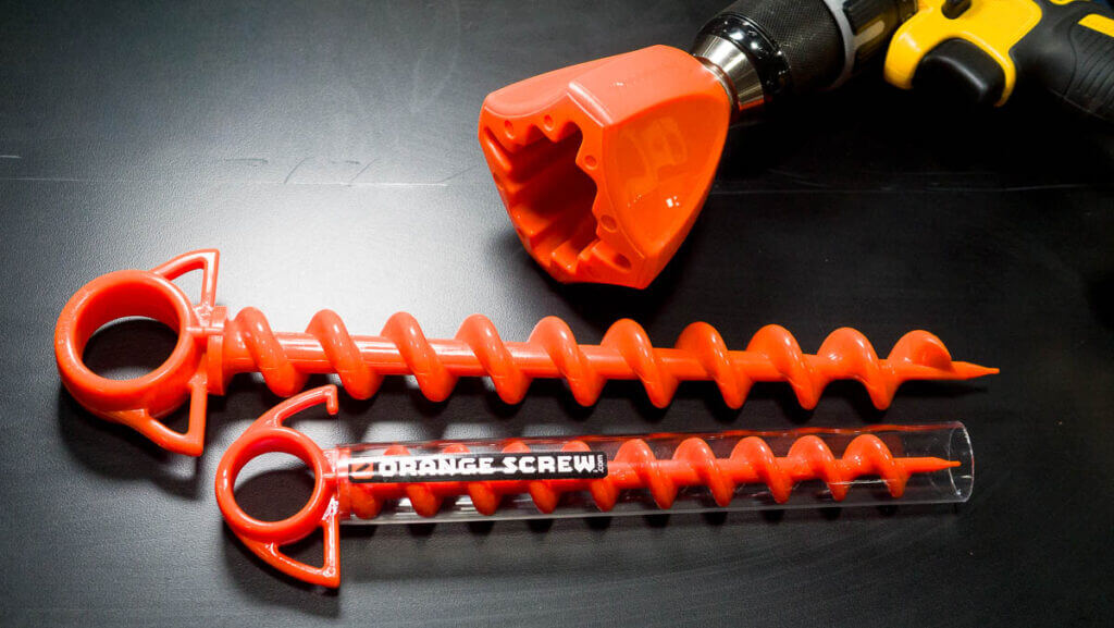 Close up of the two screws in two sizes on a black table top with the drill adapter shown, too.