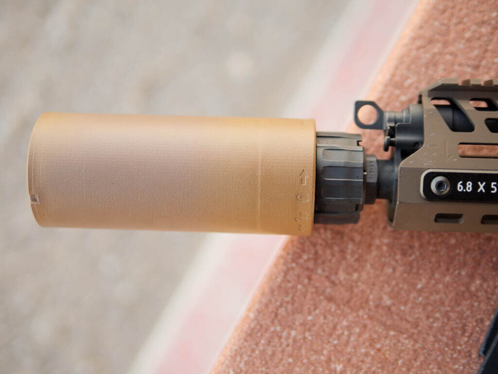 Close up of the shorter suppressor attached to the barrel.