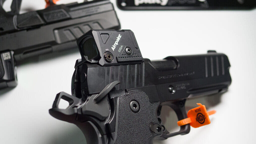 a Prodigy pistol pointing down at the table with the optic attached.
