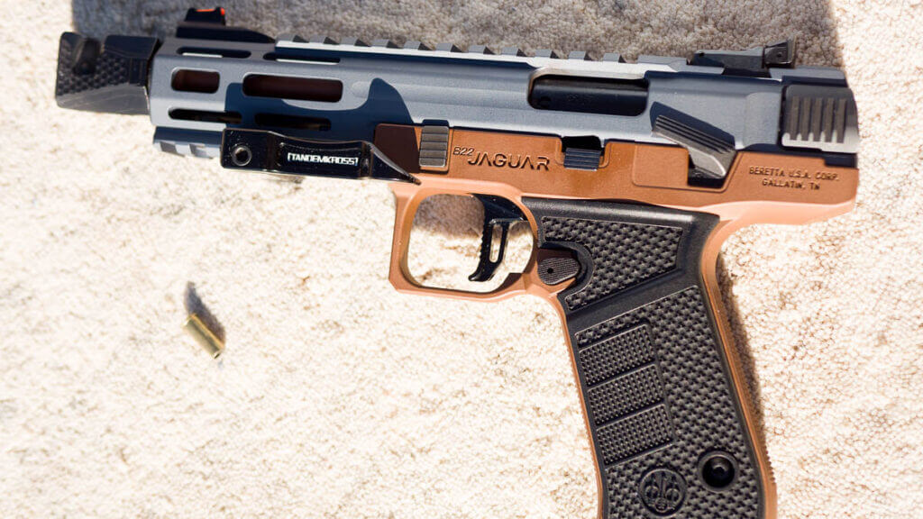 The whole gun lying on a table facing left with a spent .22 case nearby.