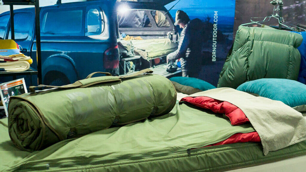 The bed roll rolled up ontop of the bedroll unrolled, a printed backdrop in the background.