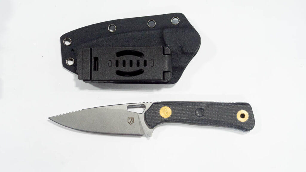 The whole knife on a white table with sheath.