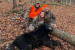 Janelle Miller with her father and grandfather posing behind her harvested black bear in Freedom, New York.