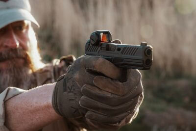 A man shooting a pistol with the Steiner MP5-C red dot on it.