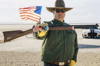 Henry America's 250th Anniversary Tribute Edition lever-action rifle with a patriotic American flag receiver finish displayed outdoors.