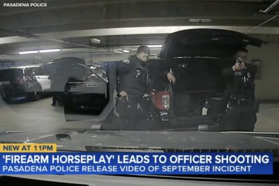 A Pasadena police officer points a handgun toward a patrol vehicle inside a department parking garage moments before an accidental shooting during what officials described as firearm horseplay involving loaded weapons.