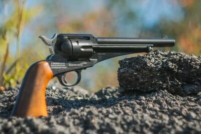 Winchester Single Action Western Revolver CO2-powered BB and pellet revolver resting on rocks outdoors.