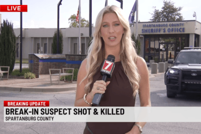 WSPA 7 News reporter stands outside the Spartanburg County Sheriff’s Office during a live report on a fatal Chesnee home break-in.