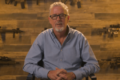 Daniel Defense founder Marty Daniel discusses the company’s 25-year history with rifles displayed behind him.
