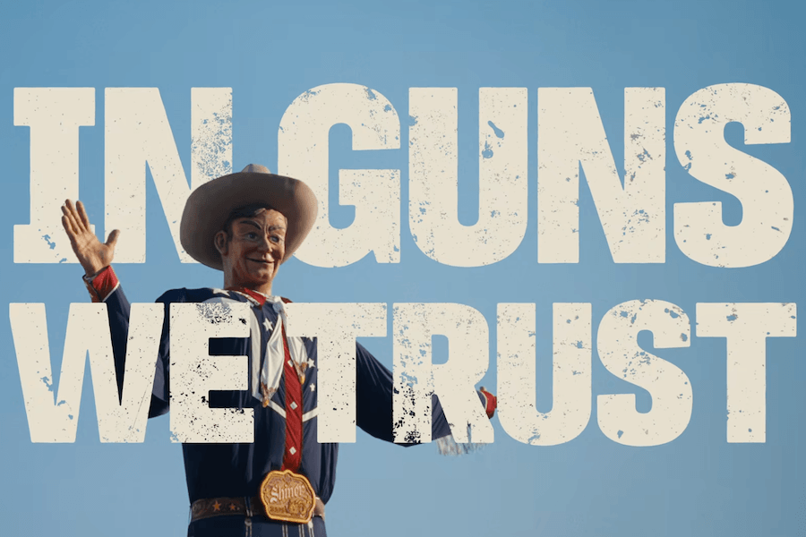 In Guns We Trust documentary title displayed over the Big Tex cowboy statue against a blue sky.